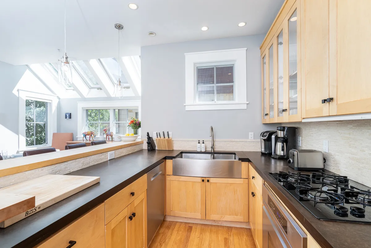 A closer look at the kitchen sink area, featuring sleek stainless steel appliances, wooden cabinetry, and large windows that bathe the space in natural light. The layout is open, offering generous counter space and a welcoming atmosphere for family cooking or entertaining.