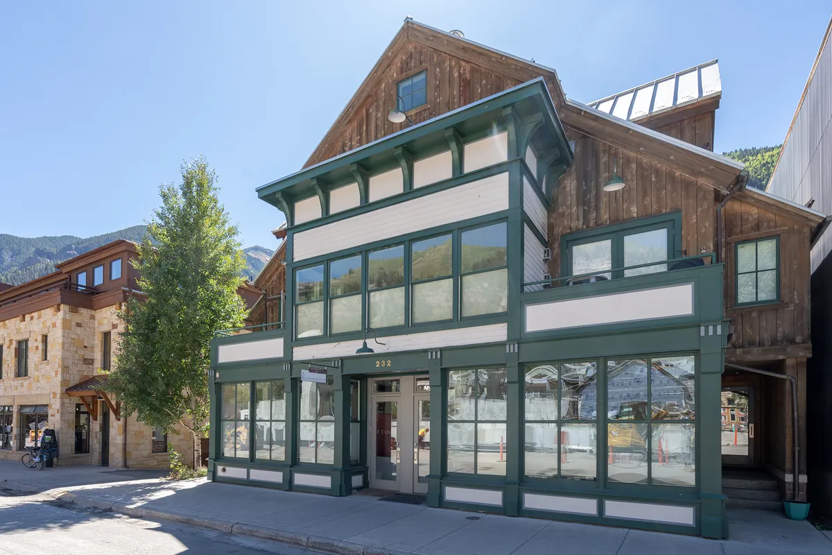 A view of the home's exterior featuring inviting architectural details, large windows, and a rustic wooden facade. The scene feels lively and approachable, hinting at the home's proximity to Telluride's vibrant Main Street and local happenings.