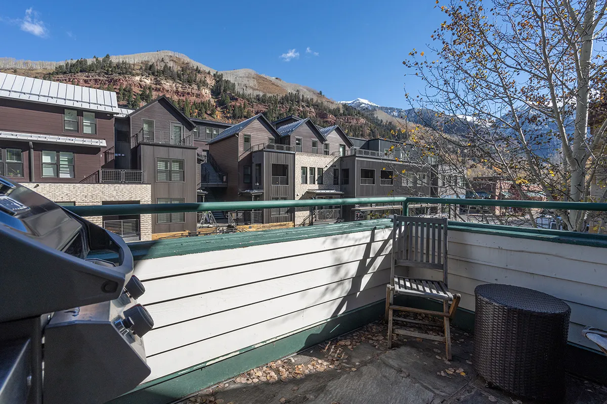 A tranquil balcony space with comfortable seating and a grill, overlooking sweeping mountain views—ideal for relaxing after a day of exploration or sharing a meal outdoors as the sun sets.